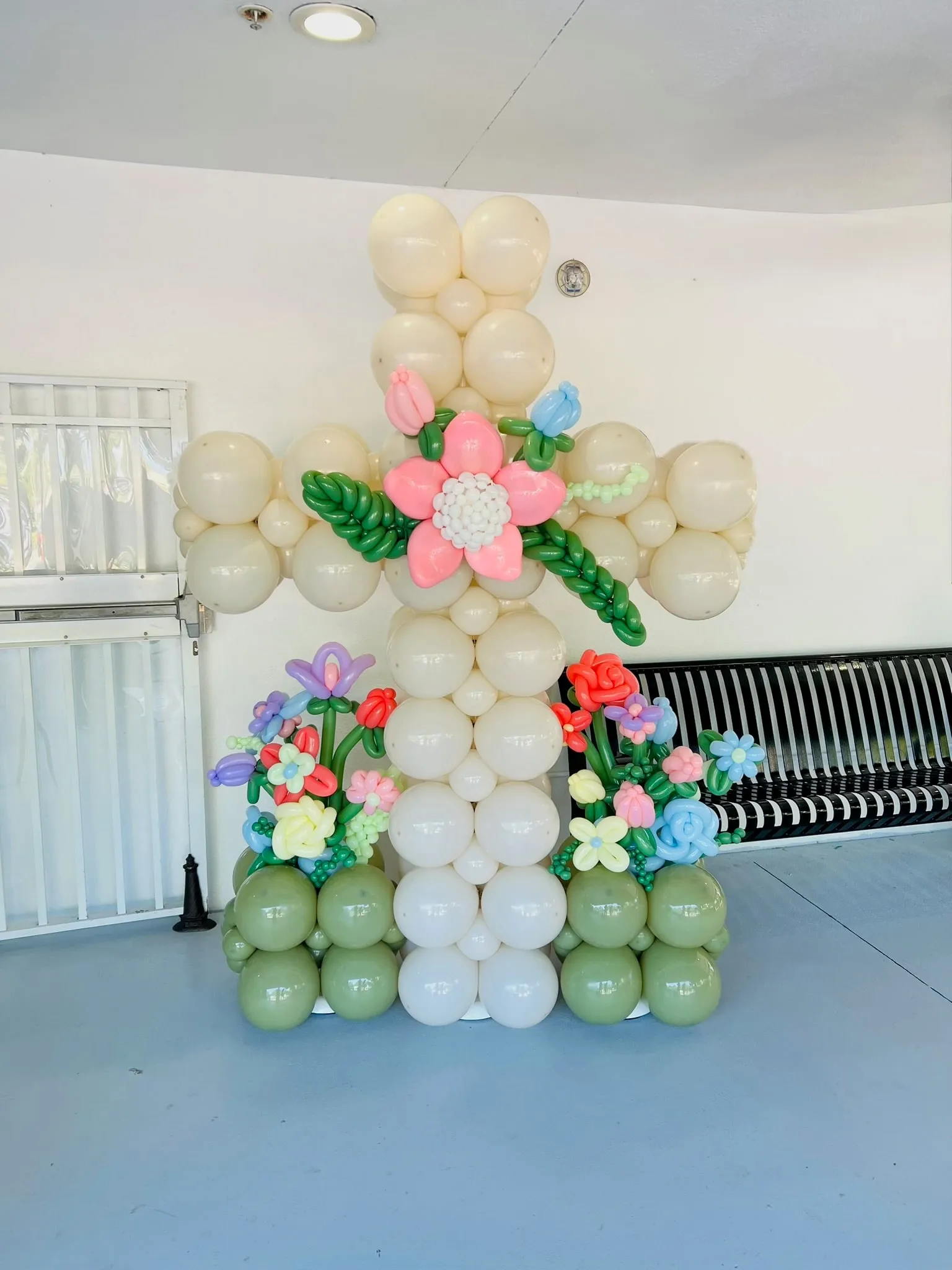 Cream balloon cross with twisted balloon flowers at its center and base
