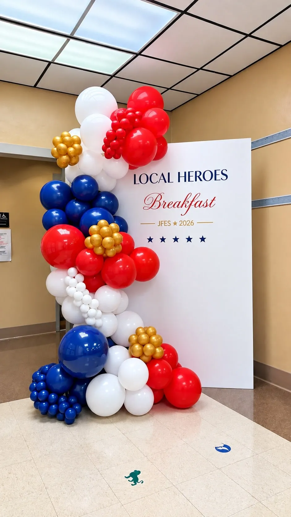 Front view of a red, white, navy and gold balloon garland beside an event backdrop