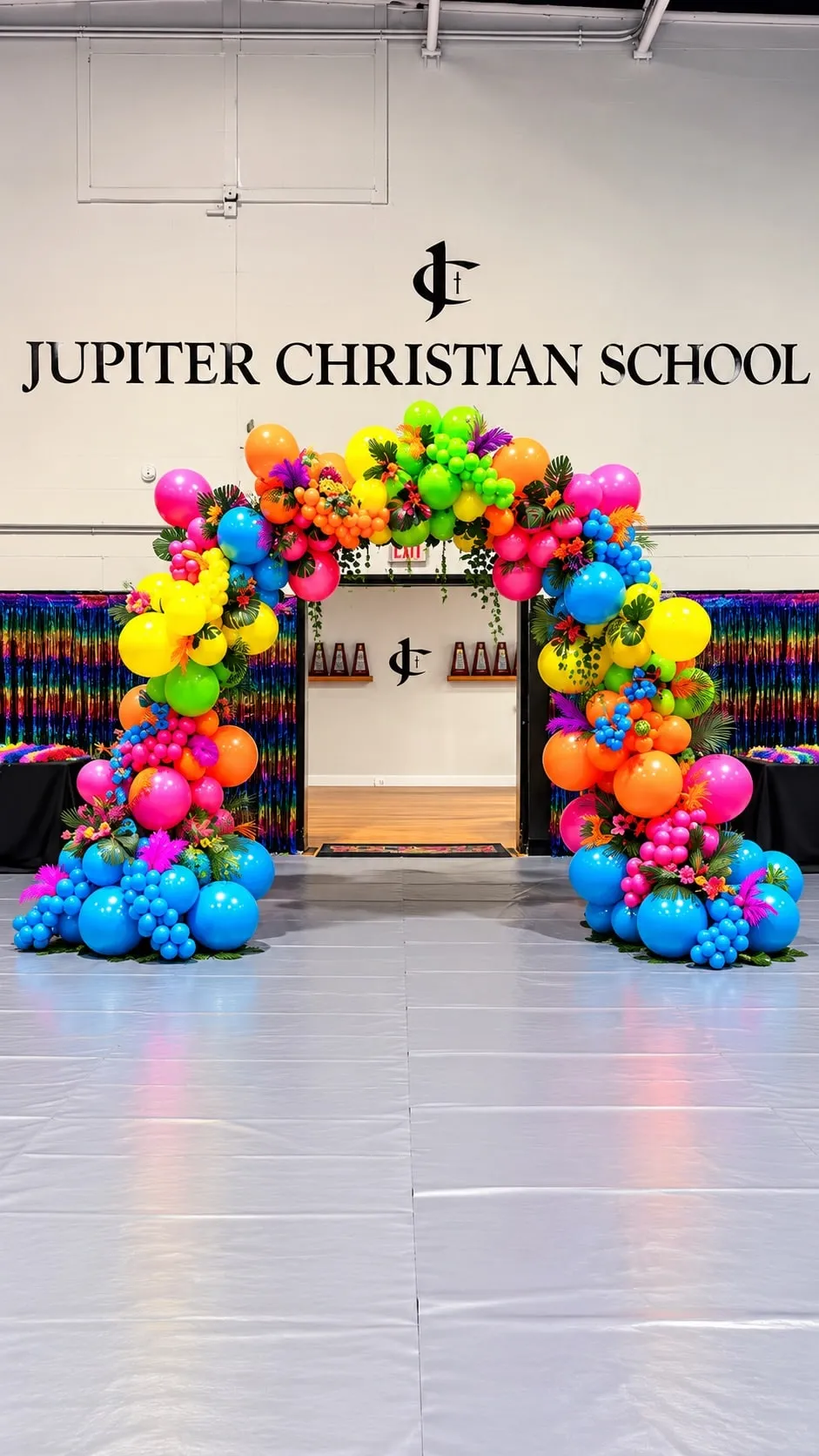 Full balloon arch in neon colors with tropical flowers in front of a school doorway