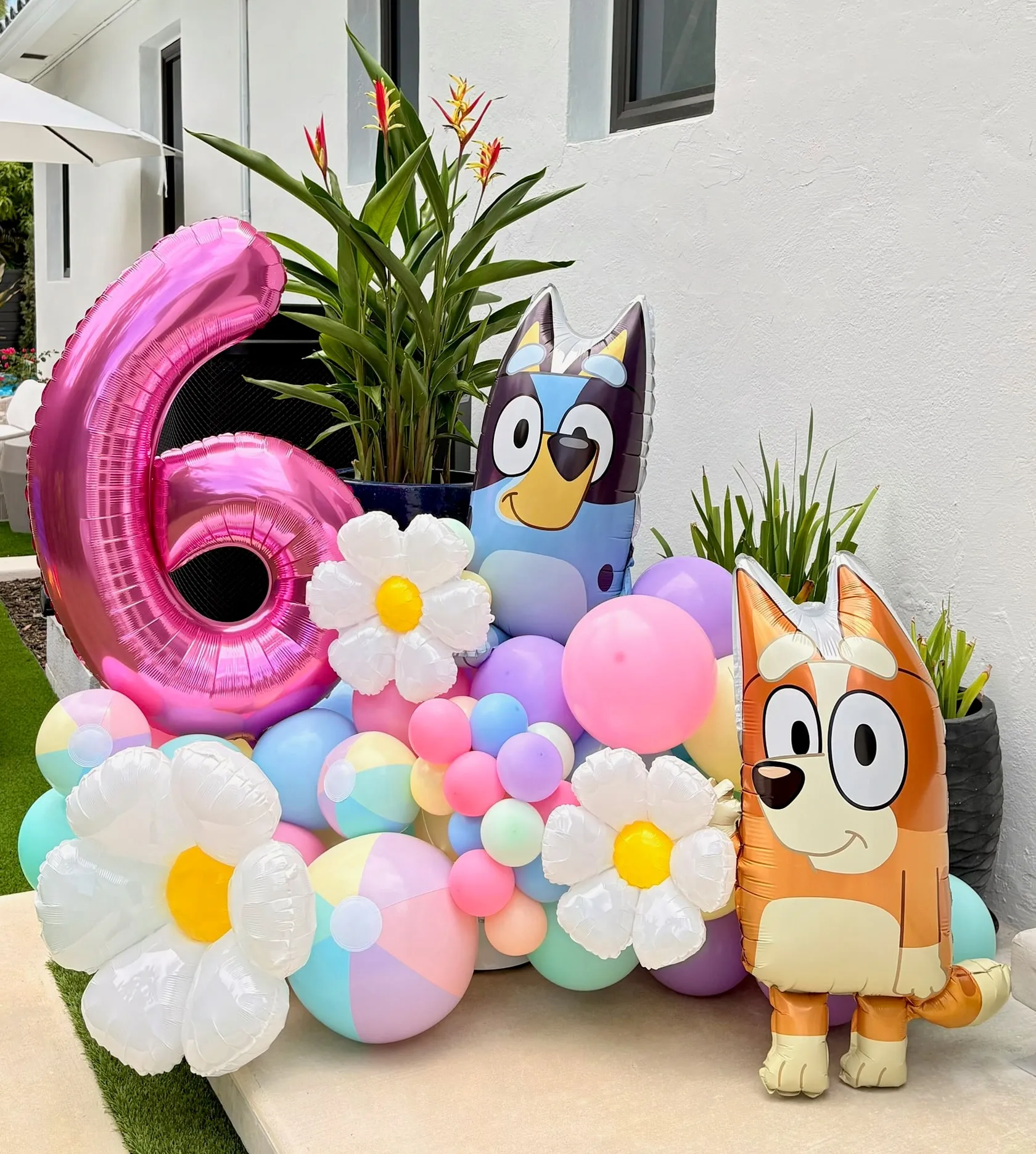 Pastel balloon cluster with daisy balloons, a large pink number six and two cartoon dog balloons