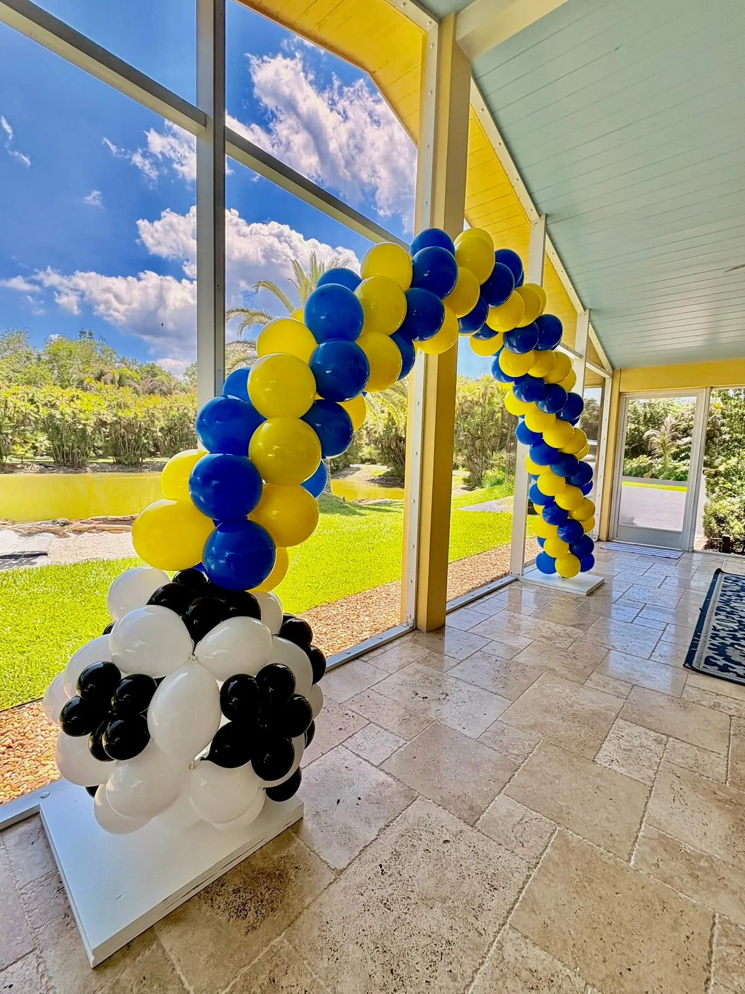Blue and yellow spiral balloon arch with a black and white soccer ball base