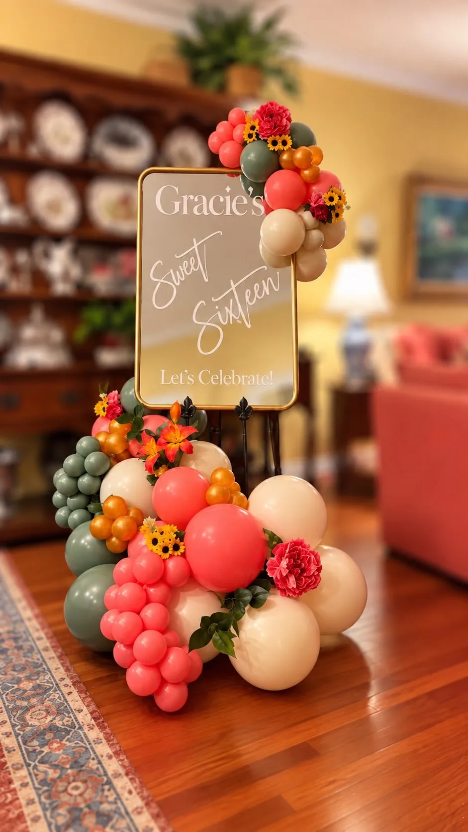 Welcome sign on an easel dressed with coral, sage and cream balloons and flowers