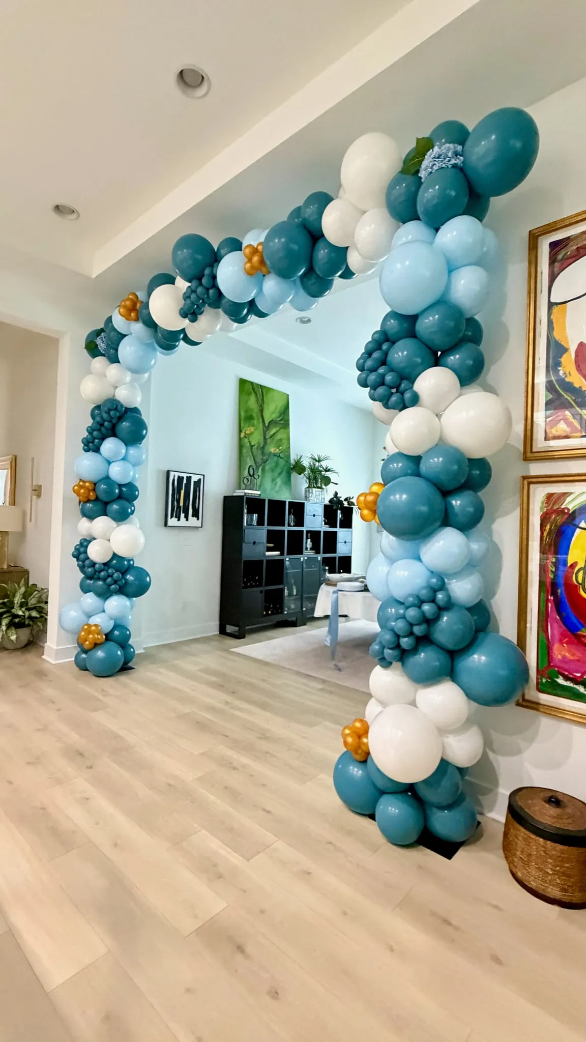 Organic balloon arch in teal, light blue and white around a wide doorway