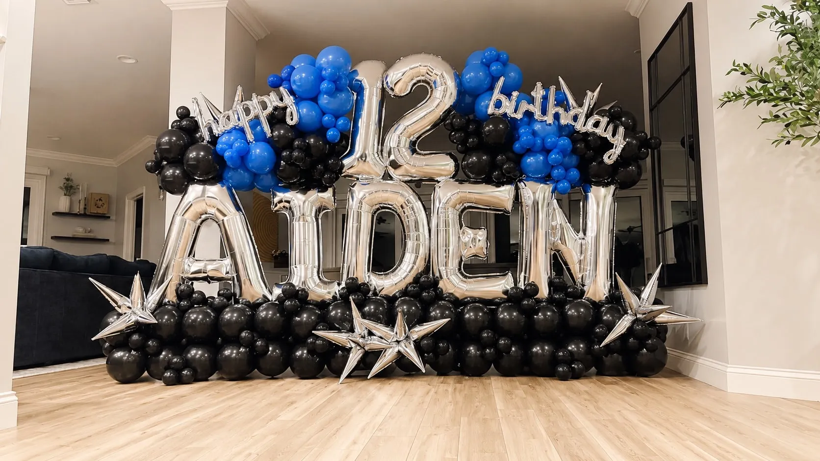 Large silver foil letters and a number twelve above a row of black and blue balloons