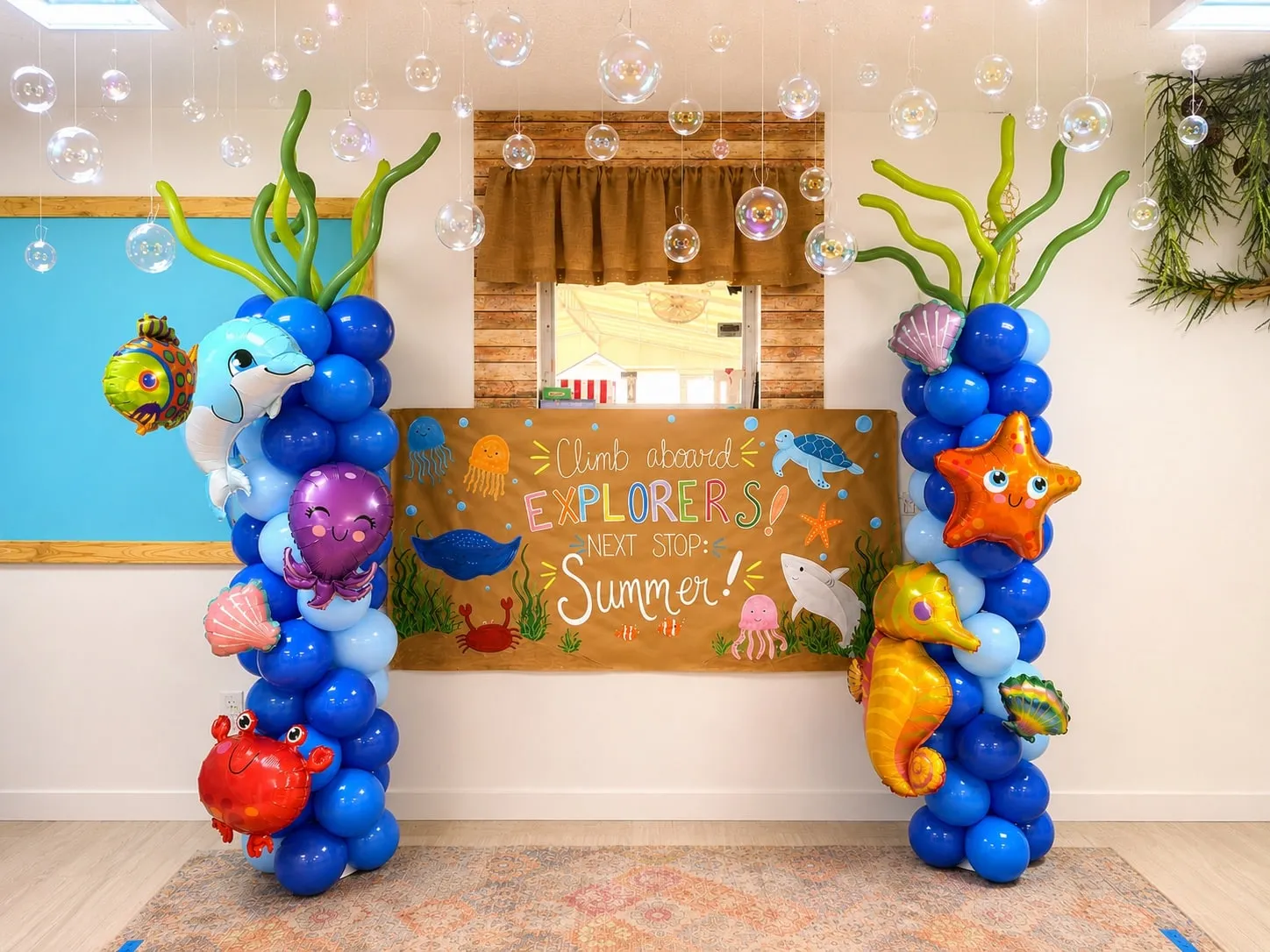 Two blue balloon columns decorated with sea creature balloons on either side of a classroom display